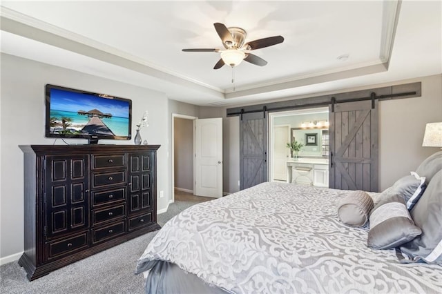 bedroom featuring connected bathroom, a tray ceiling, light colored carpet, and a barn door