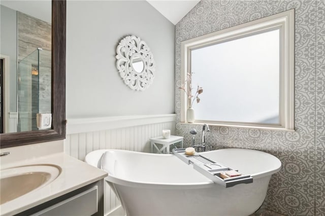 bathroom with vanity, vaulted ceiling, and a bathtub