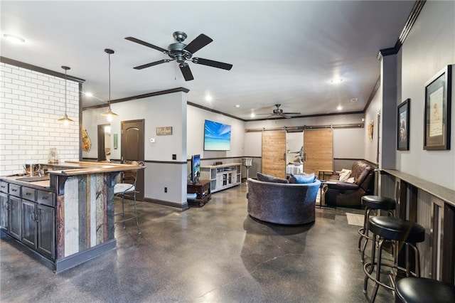 living room featuring sink, crown molding, a barn door, and ceiling fan