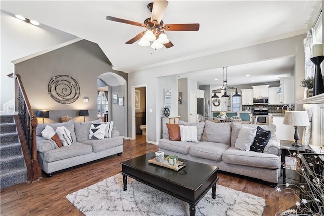 living room featuring lofted ceiling, a wealth of natural light, dark wood-type flooring, and ornamental molding