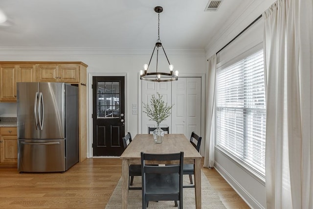 dining area featuring ornamental molding, light wood-type flooring, visible vents, and a notable chandelier