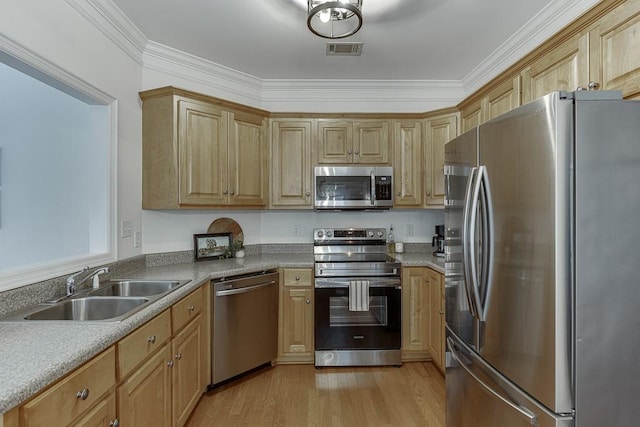 kitchen featuring stainless steel appliances, a sink, visible vents, light wood-type flooring, and crown molding