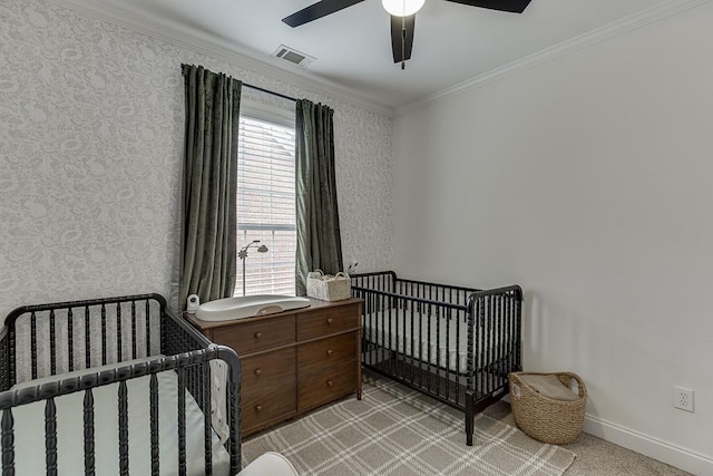 bedroom featuring crown molding, visible vents, a crib, baseboards, and wallpapered walls