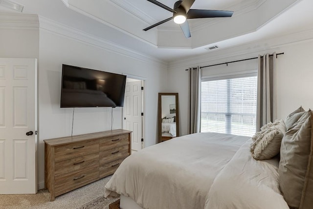 bedroom with light colored carpet, a tray ceiling, visible vents, and crown molding