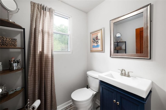 bathroom with toilet, vanity, and baseboards
