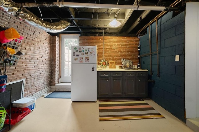 interior space featuring freestanding refrigerator and brick wall