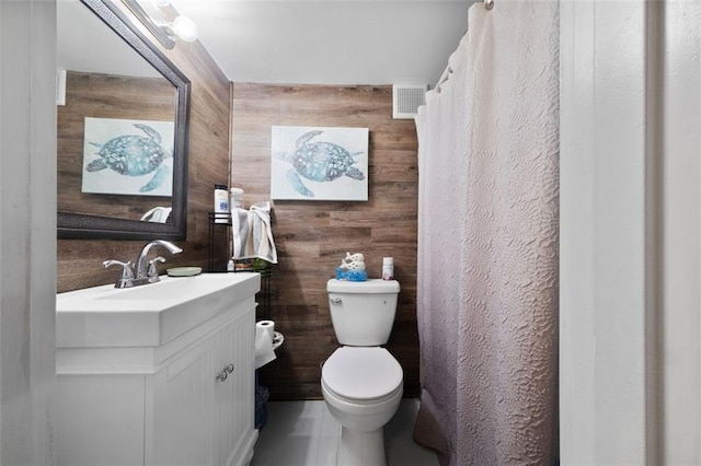 full bathroom featuring wood walls, visible vents, toilet, tile patterned floors, and vanity
