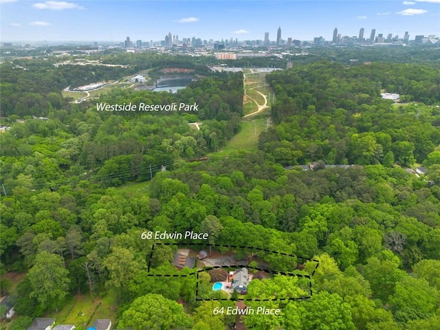 drone / aerial view featuring a city view and a wooded view