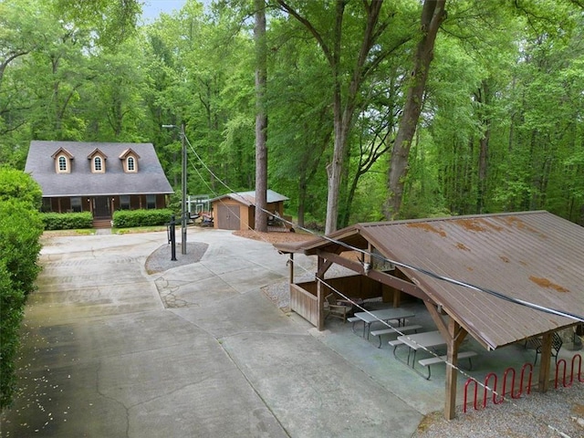 view of patio / terrace featuring a wooded view and an outbuilding