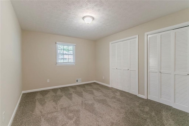 545 Fayetteville Rd, Fairburn, GA 30213 - unfurnished bedroom with two closets, carpet flooring, a textured ceiling, and baseboards