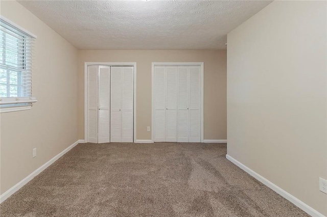 545 Fayetteville Rd, Fairburn, GA 30213 - unfurnished bedroom with two closets, a textured ceiling, carpet floors, and baseboards