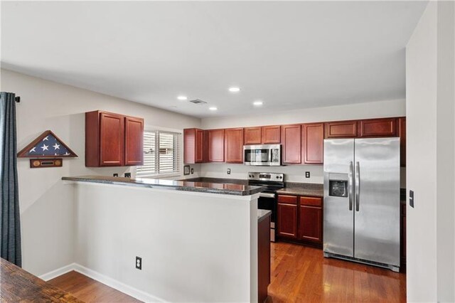 kitchen with kitchen peninsula, dark hardwood / wood-style flooring, and stainless steel appliances