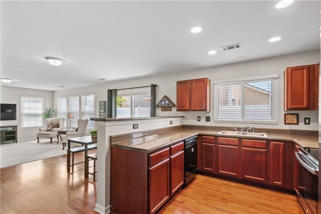 kitchen with kitchen peninsula, black dishwasher, a wealth of natural light, and sink