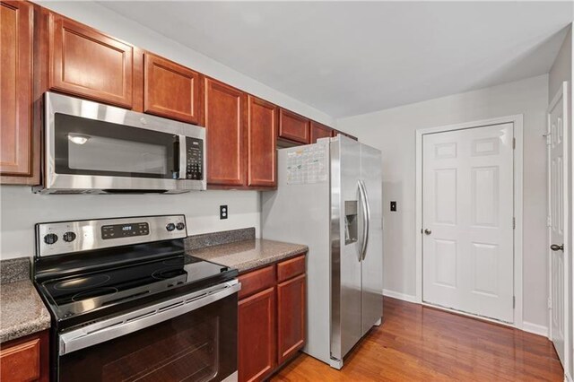 kitchen with appliances with stainless steel finishes and light hardwood / wood-style flooring