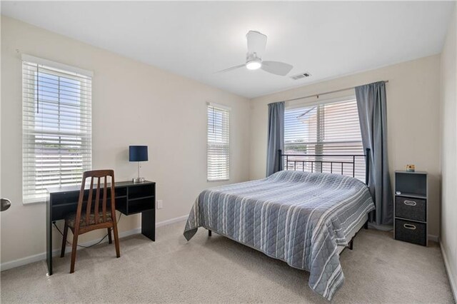 bedroom featuring light colored carpet, multiple windows, and ceiling fan