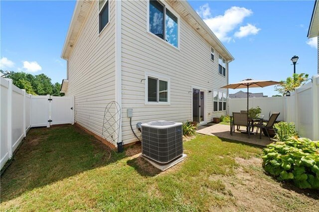 rear view of property with a yard, cooling unit, and a patio