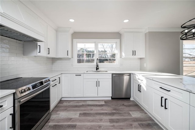 kitchen featuring custom exhaust hood, stainless steel appliances, light wood-style flooring, white cabinets, and a sink