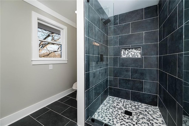 bathroom with a stall shower, tile patterned flooring, toilet, and baseboards