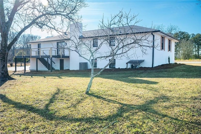 back of house with stairs, a lawn, a wooden deck, and stucco siding