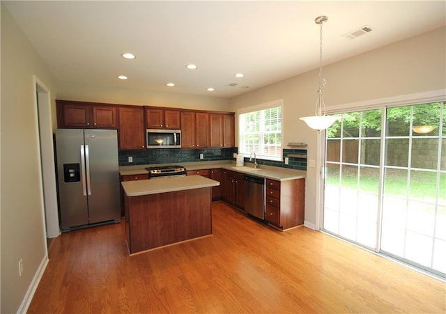 942 Idlewood Dr, Canton, GA 30115 - kitchen featuring appliances with stainless steel finishes, a sink, a center island, light wood-style floors, and tasteful backsplash