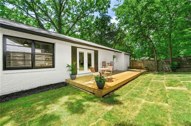 back of property with a lawn, a wooden deck, and french doors