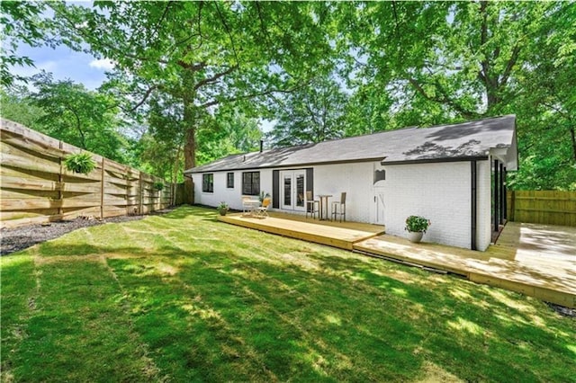 rear view of property with a yard, a wooden deck, and french doors