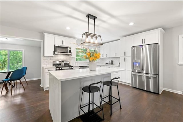 kitchen with backsplash, stainless steel appliances, pendant lighting, white cabinets, and a kitchen island