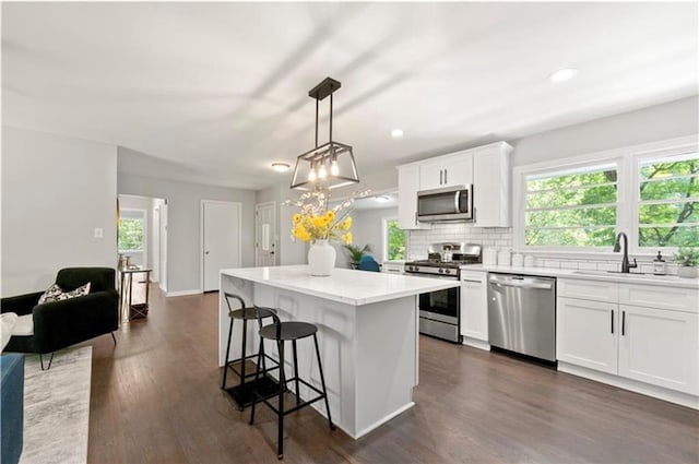 kitchen featuring a kitchen island, white cabinetry, hanging light fixtures, and appliances with stainless steel finishes