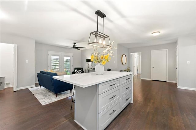 kitchen featuring pendant lighting, a breakfast bar, a center island, ceiling fan, and white cabinetry