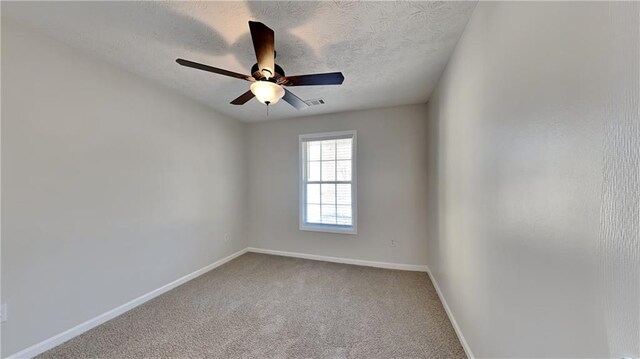 carpeted spare room with a ceiling fan, visible vents, a textured ceiling, and baseboards