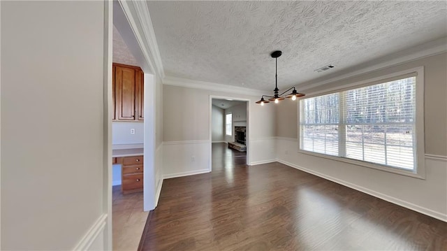 unfurnished dining area featuring a textured ceiling, dark wood finished floors, visible vents, and crown molding