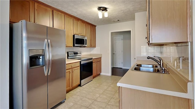 kitchen featuring stainless steel appliances, tasteful backsplash, a sink, and light countertops