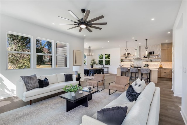 living area featuring recessed lighting, baseboards, wood finished floors, and ceiling fan with notable chandelier