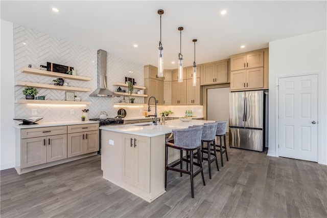 kitchen featuring a sink, light countertops, appliances with stainless steel finishes, wall chimney exhaust hood, and open shelves