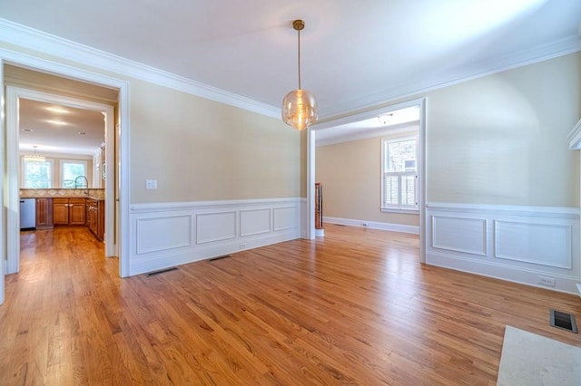 980 Windsor Place Cir, Grayson, GA 30017 - unfurnished dining area with ornamental molding, light wood finished floors, a wainscoted wall, a decorative wall, and a sink
