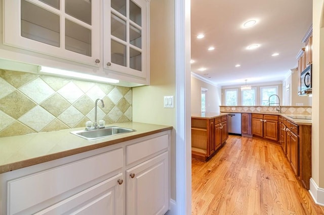 980 Windsor Place Cir, Grayson, GA 30017 - kitchen featuring a sink, crown molding, light wood-type flooring, brown cabinetry, and backsplash