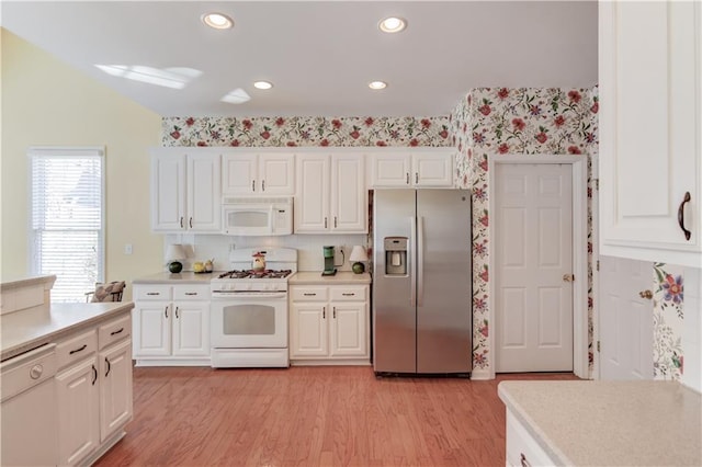 kitchen with white cabinetry, light hardwood / wood-style floors, white appliances, and backsplash