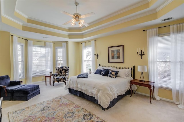 bedroom featuring ceiling fan, multiple windows, light carpet, and a raised ceiling