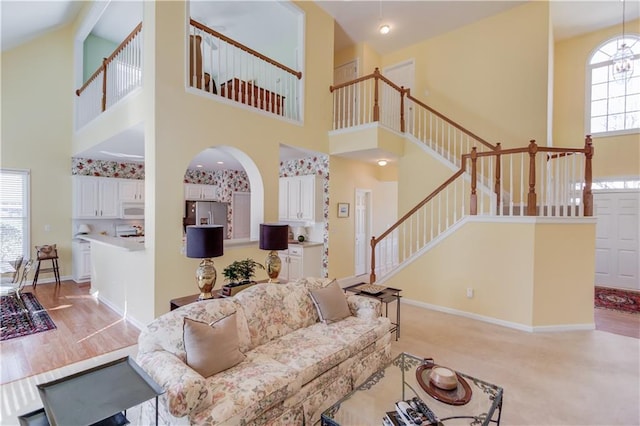 living room with light carpet, a towering ceiling, and a wealth of natural light