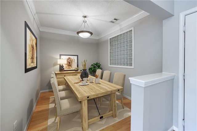 dining area featuring crown molding, light hardwood / wood-style floors, and a textured ceiling