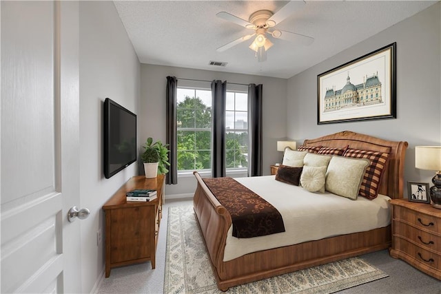 bedroom with a textured ceiling, ceiling fan, and light carpet