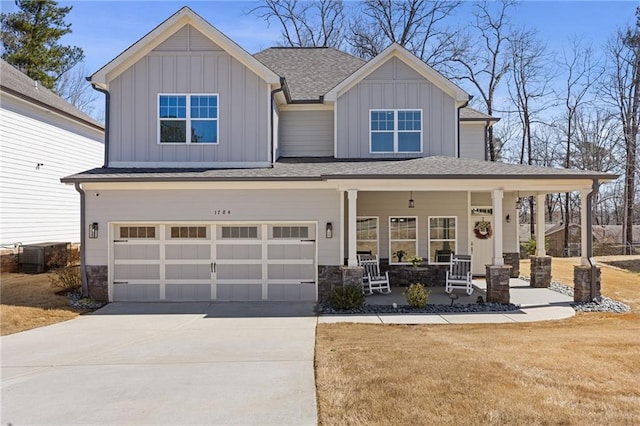 craftsman inspired home featuring board and batten siding, central air condition unit, a porch, concrete driveway, and a garage