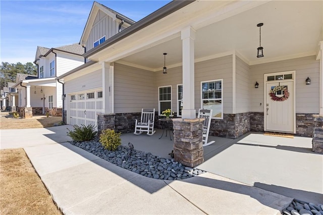 exterior space with driveway, a porch, a garage, stone siding, and board and batten siding