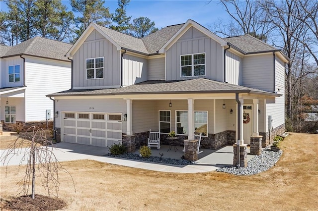 view of front of property with driveway, covered porch, a garage, stone siding, and board and batten siding