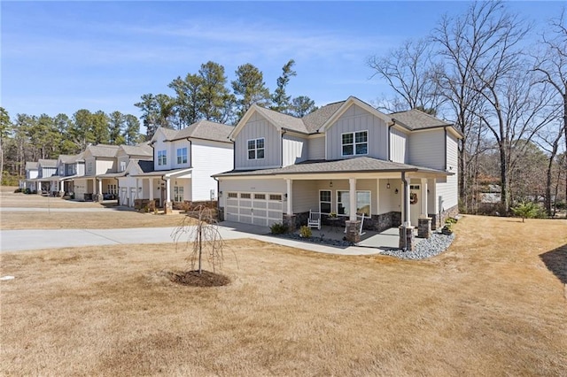 modern farmhouse with a front yard, a porch, an attached garage, concrete driveway, and board and batten siding