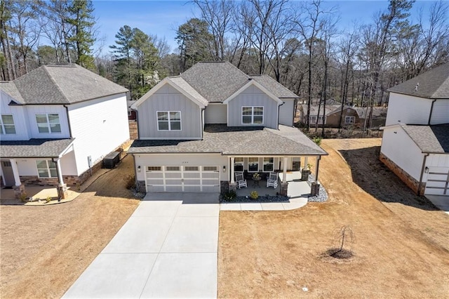 view of front of house featuring covered porch, concrete driveway, a front lawn, a garage, and board and batten siding