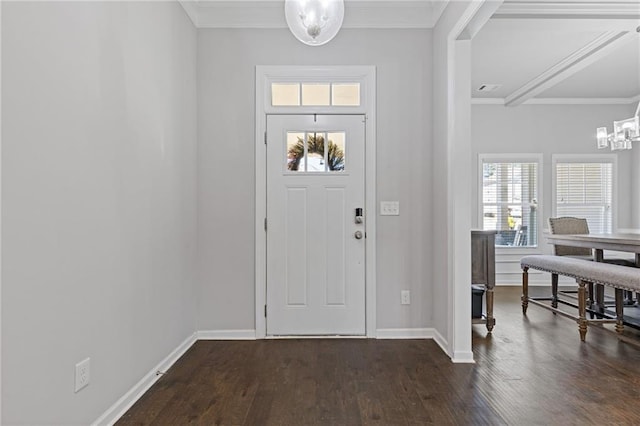 foyer entrance with an inviting chandelier, a healthy amount of sunlight, dark wood-style flooring, and ornamental molding