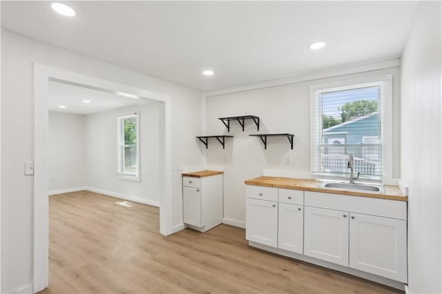 kitchen with open shelves, wood counters, plenty of natural light, and a sink