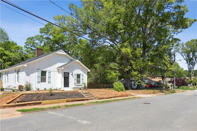 view of front of house with board and batten siding, fence, and a chimney