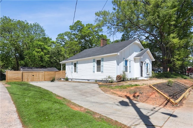 bungalow-style house with fence, board and batten siding, a gate, a chimney, and driveway